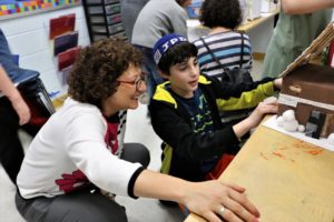 Head of School Naomi Reem hears about a fourth grader's model house project.