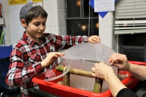 A fifth grader participates in an activity in the fourth grade classroom.