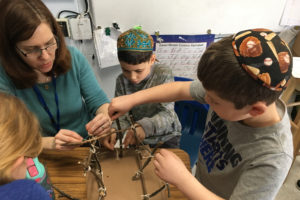 Science Specialist Elana Cohen helps third graders construct a Native American structure.