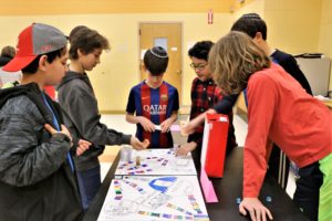 Sixth graders gather around a game board at the Odysseus Game Fair.