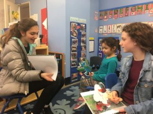 A sixth grader reads a story to a child at CentroNia.