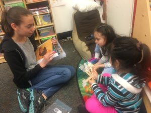 A sixth grader reads a story to a child at CentroNia.