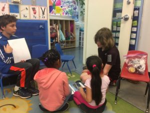 A sixth grader reads a story to a child at CentroNia.