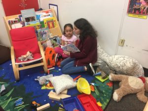 A sixth grader reads a story to a child at CentroNia.