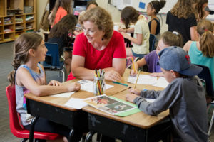 Hebrew teacher Gila Efrati sits at a desk with students.