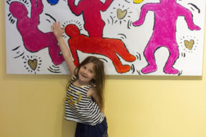 A child points to her outline on the mural.