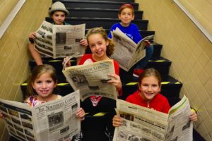 Students pose with copies of the Northwest Current, a local newspaper.