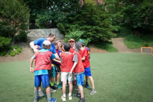 Athletic Director Yonah Singer leads a huddle of students on the field.