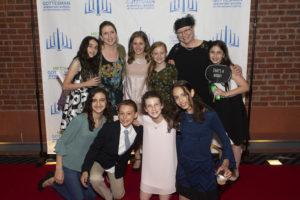 Sixth grade teacher Fani Bettmann, Director of Jewish Life Sharon Freundel, and sixth graders strike a pose on the red carpet.