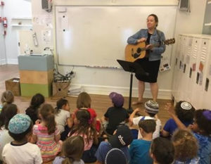 Early Childhood Director Melissa Davis plays guitar as she leads a sing-along on Mitzvah Day.