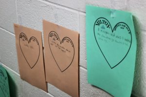 Three mitzvah hearts decorate a stairwell. They read, "learned Torah," "I visited my Grandma when she went to the hospital," and "I helped my grandma go down the stairs."