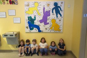 Pre-kindergartners pose in front of one section of the mural.