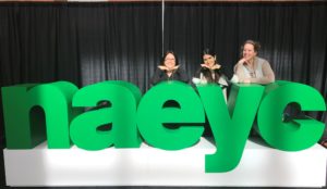 Atelierista Judy Kimel, Pedagogista Laura Cohen, and Director of Early Childhood Melissa Davis pose on a tall row of block letters spelling "NAEYC."