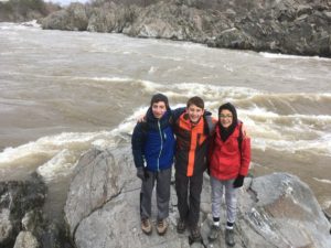 Middle school students pose together on the rocks above the Potomac River at Great Falls National Park.