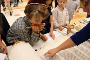 Judaic Studies teacher Nechama Malkiel points out a detail in a Torah scroll to a student during the Third Grade Chagigat HaChumash (Celebration of the Torah).